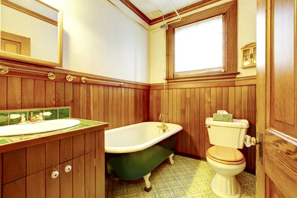 Brown and green antique bathroom with plank paneled walls and bathtub