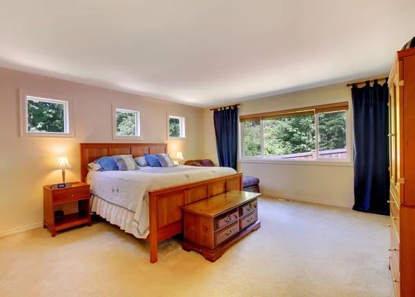 Bedroom interior with beige carpet floor and dark blue curtains.