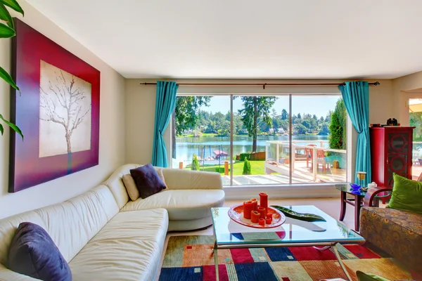 Bright classic living room interior with white leather couch and beautiful water view.