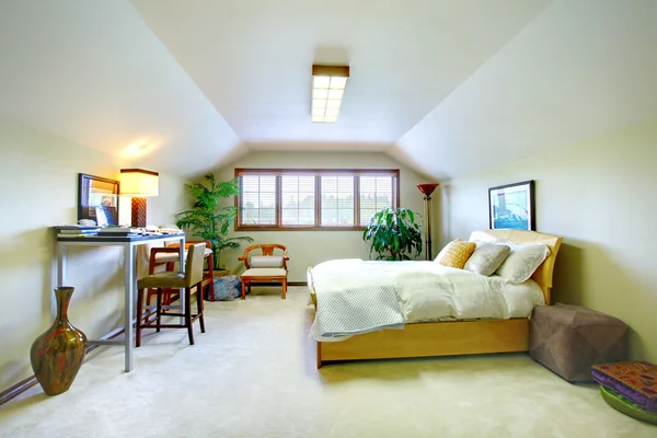 Elegant upstairs bedroom in soft tones with vaulted ceiling and study area.