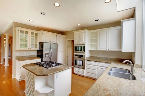 Classic American kitchen interior with white cabinets and built-in stainless steel fridge.