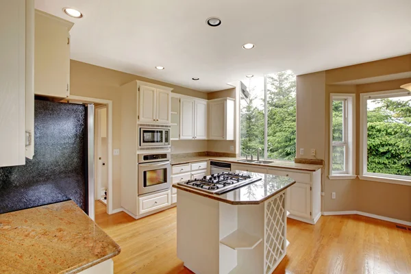 White small classic American kitchen interior with kitchen island and granite counter top.