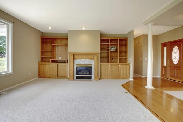 Living room in open floor plan with foyer view and wooden entrance door.