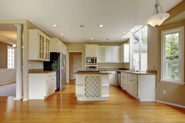 Small classic American kitchen interior with white cabinets and hardwood floor..