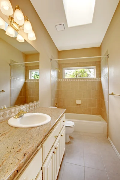 Light bathroom interior with wooden cabinets and tile floor.