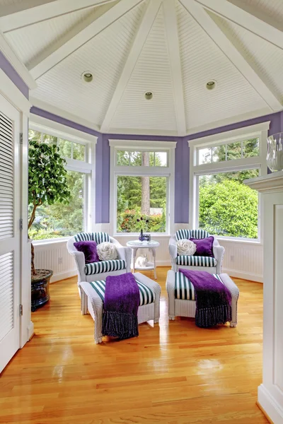 Vaulted ceiling living room in purple tones with two stripped armchairs..
