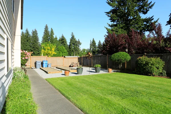 Fenced back yard with green lawn, beds