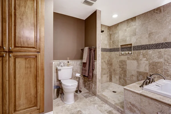 Empty bathroom interior. Light brown tile, bath tub and toilet