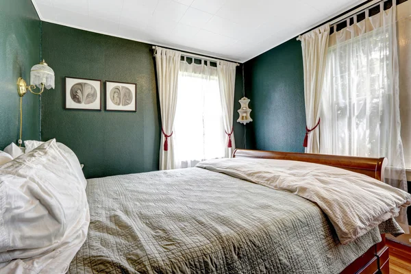 Small bedroom with wooden bed, dark green walls