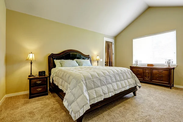 Master bedroom with deep brown furniture set and vaulted ceiling.