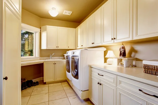 White laundry room interior with tile floor and cabinets.
