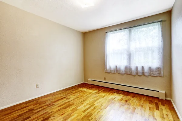 Small empty basement room with hardwood floor and beige walls