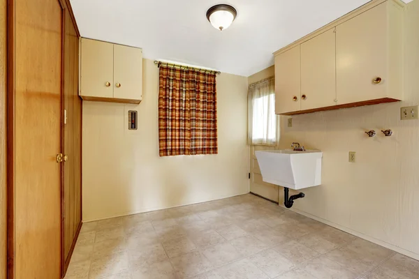 Laundry room with beige walls and tile floor. furnished with cabinets and built-in wardrobe