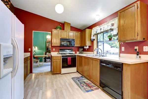 Kitchen room with red wall, vaulted ceiling and dining table set.