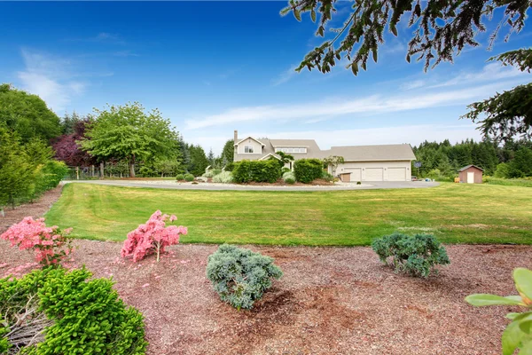 Large beige house with white trim, and well kept lawn