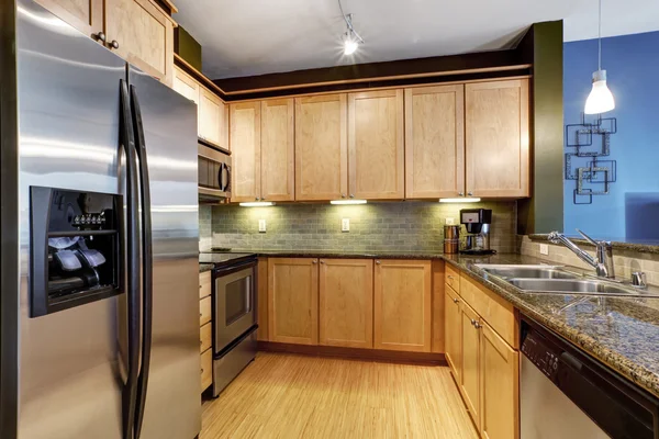 Light brown kitchen with hardwood floor and granite.