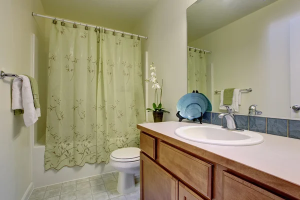 Bathroom interior with tile floor, wooden cabinets and big mirror