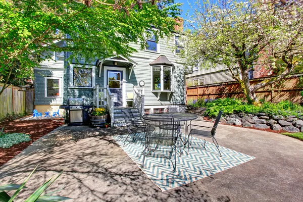 House exterior. View of concrete floor patio area with table set and barbecue.