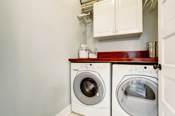 Small laundry room with tile floor, door, and washer dryer set.