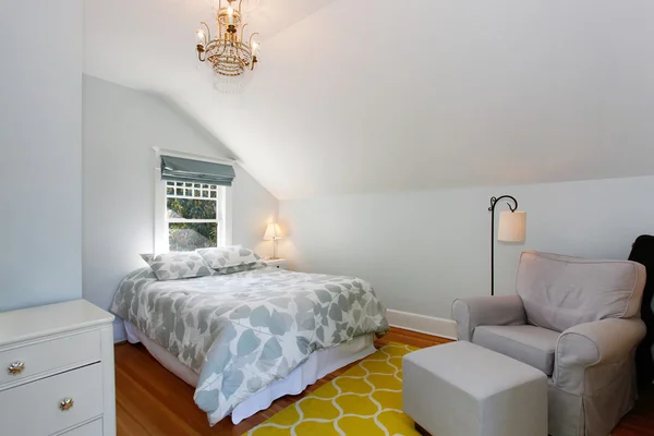 Cozy attic bedroom with white walls and yellow rug.