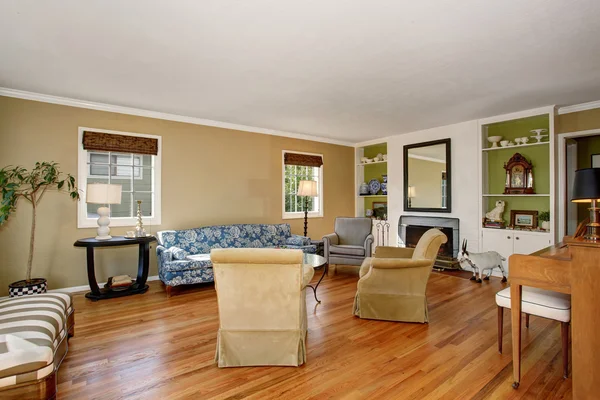 Classic American living room interior. Beige and green walls, hardwood floor and blue sofa.