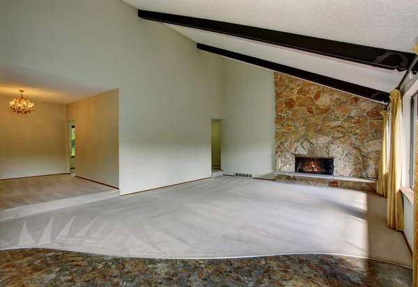 Spacious unfurnished living room interior with high vaulted ceiling and stone trim fireplace