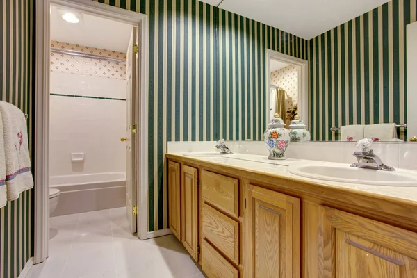 Nice bathroom interior in green tones with cabinets, double sink and tile floor.