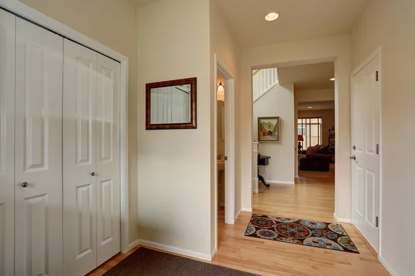 Bright hallway in creamy tones with hardwood floor.