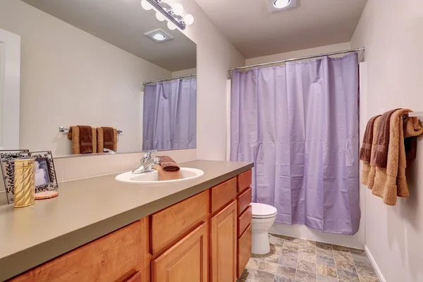 Bathroom interior with tile floor and lavender curtain.