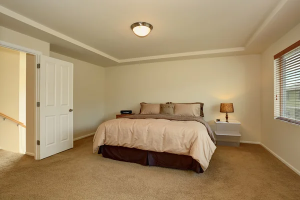 Simple bedroom interior with double bed and carpet floor.