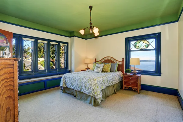 Adorable antique bedroom interior with green ceiling and blue trim.