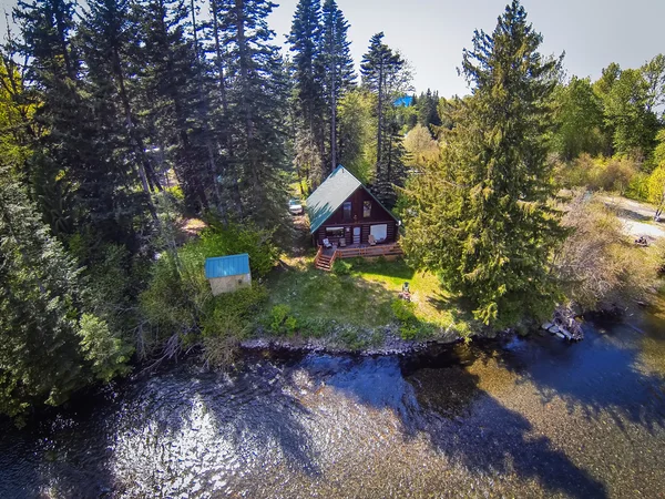 Panoramic view of cabin style home on a river bank