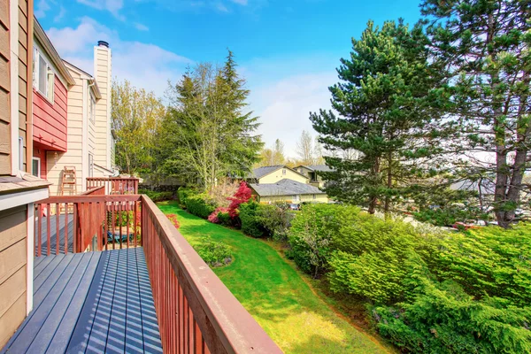 Small empty wooden porch with view of back yard