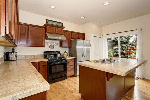 Cozy kitchen room with tile counter top, kitchen island and stainless steel fridge