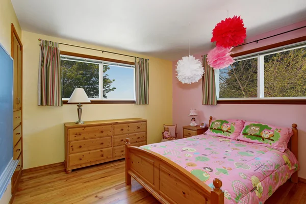Adorable girls bedroom interior with hardwood floor and pink wall.