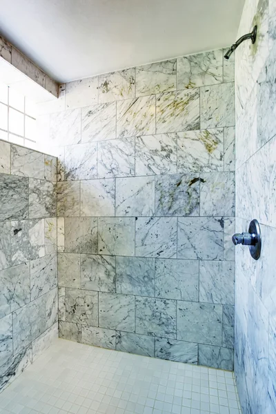Bathroom interior. Shower cabin with marble tile and small window.