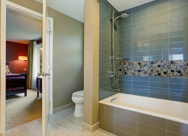 Simple yet modern bathroom interior with tile wall trim and bedroom view