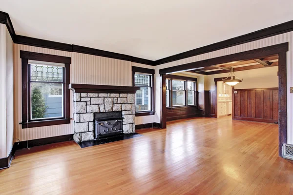 Empty Family room with antique stone fireplace and hardwood floor.