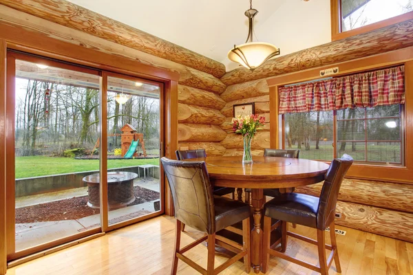 Dining table with leather chairs in log cabin house.