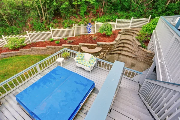 Two level backyard deck with jacuzzi on the first floor and patio area on the second one