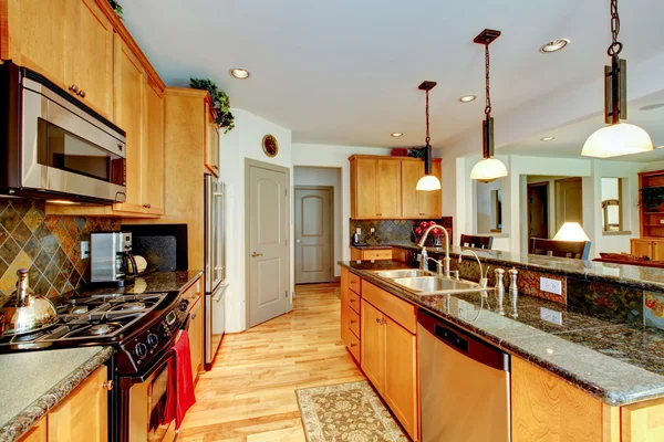 Kitchen room with brown cabinets, stainless steel, granite counter top.