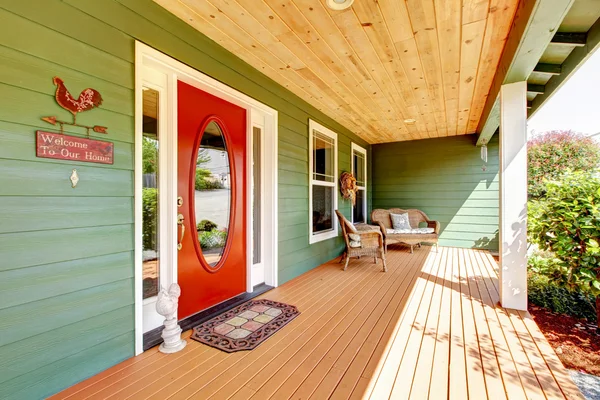 Spacious entrance porch with red door and wooden chair