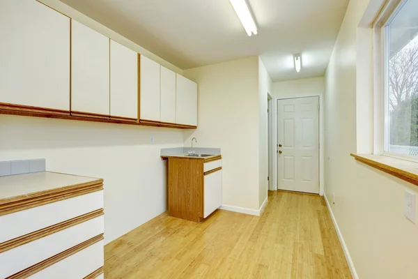 Bright laundry room interior with cabinets and hardwood flooring.