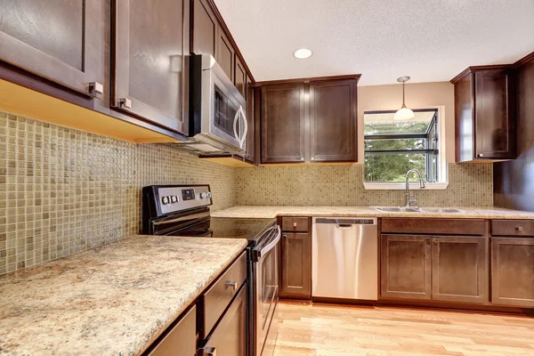 Kitchen interior with brown cabinets and granite tops.