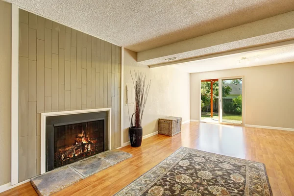 Spacious empty living room with fireplace and exit to the back yard.