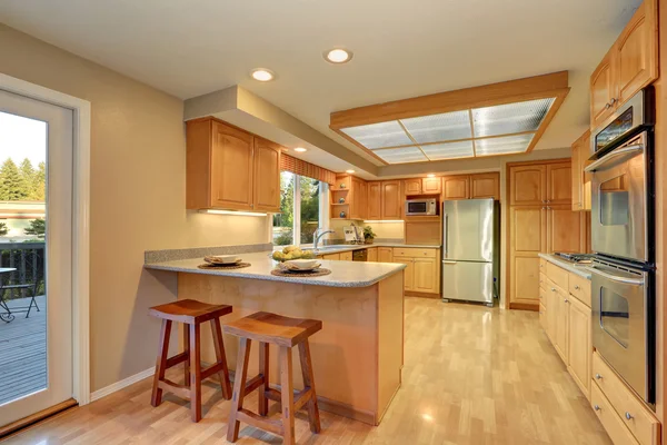 Bright wooden kitchen interior with steel appliances.