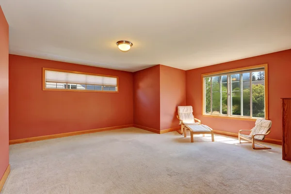 Red room with two chairs and carpet floor.