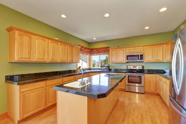 Spacious kitchen with green walls and hardwood floor