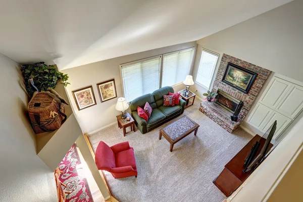 Traditional living room interior with green sofa and brick fireplace.