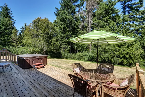 Backyard house exterior with patio area and hot tub on the walkout deck.